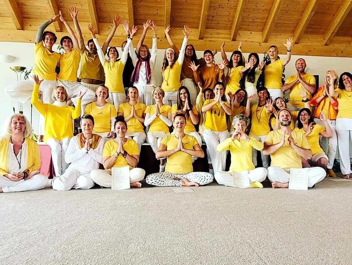 Gruppe von Yoga-Teilnehmenden in gelben Shirts in einem hellen Studio