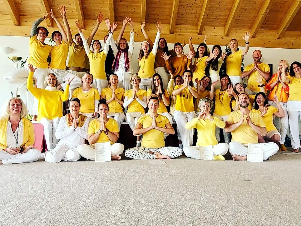 Gruppe von Yoga-Teilnehmenden in gelben Shirts in einem hellen Studio